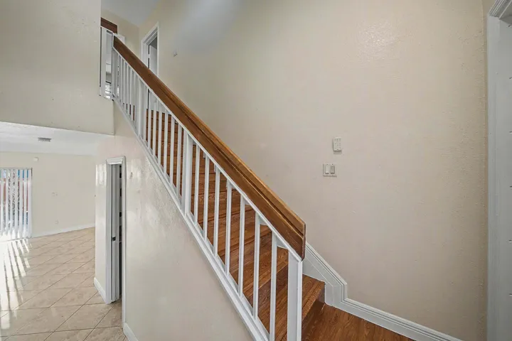 Staircase featuring wood-finish treads and handrail, white balusters, and light-toned walls