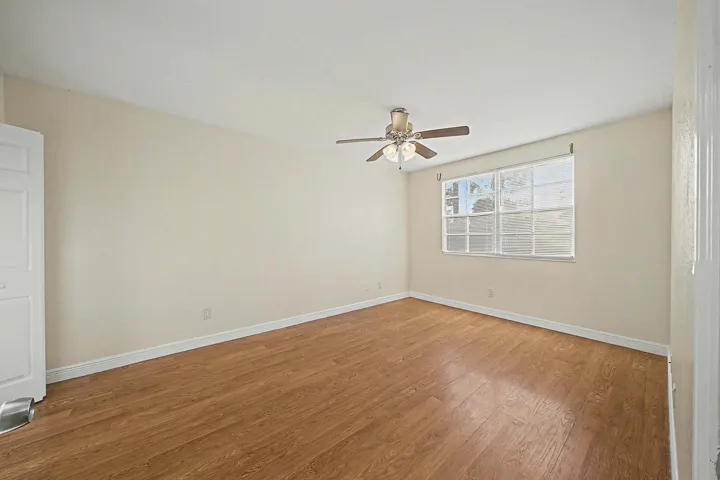 Bright interior room featuring wood-finish flooring, light-toned walls, and a ceiling fan with integrated lighting