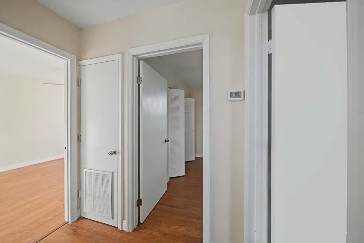 Hallway presenting multiple doorways with white trim and wood-finish flooring