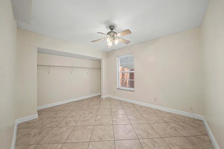Spacious room featuring neutral-toned walls, diagonal tile flooring, and a ceiling fan with integrated lighting