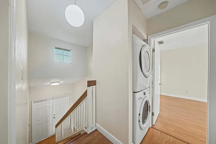 Stairwell featuring wood-finish flooring, white banister, and natural light from an upper window