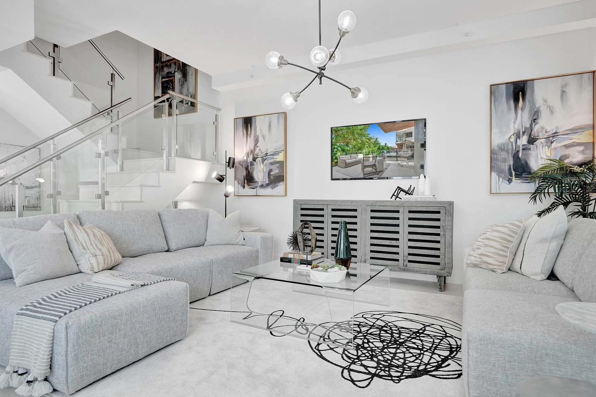 Modern open-concept living space featuring a curved sectional sofa arrangement, polished concrete flooring, and a slatted built-in media console