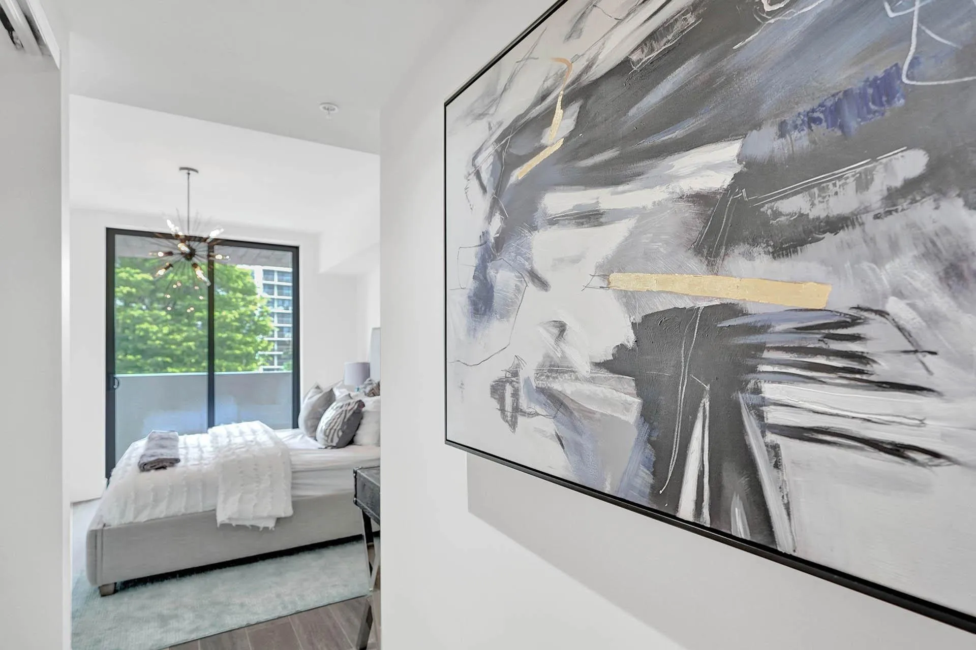 Bedroom featuring a full-height glass sliding door opening to a private balcony, a contemporary sputnik-style chandelier, and wood-finish flooring