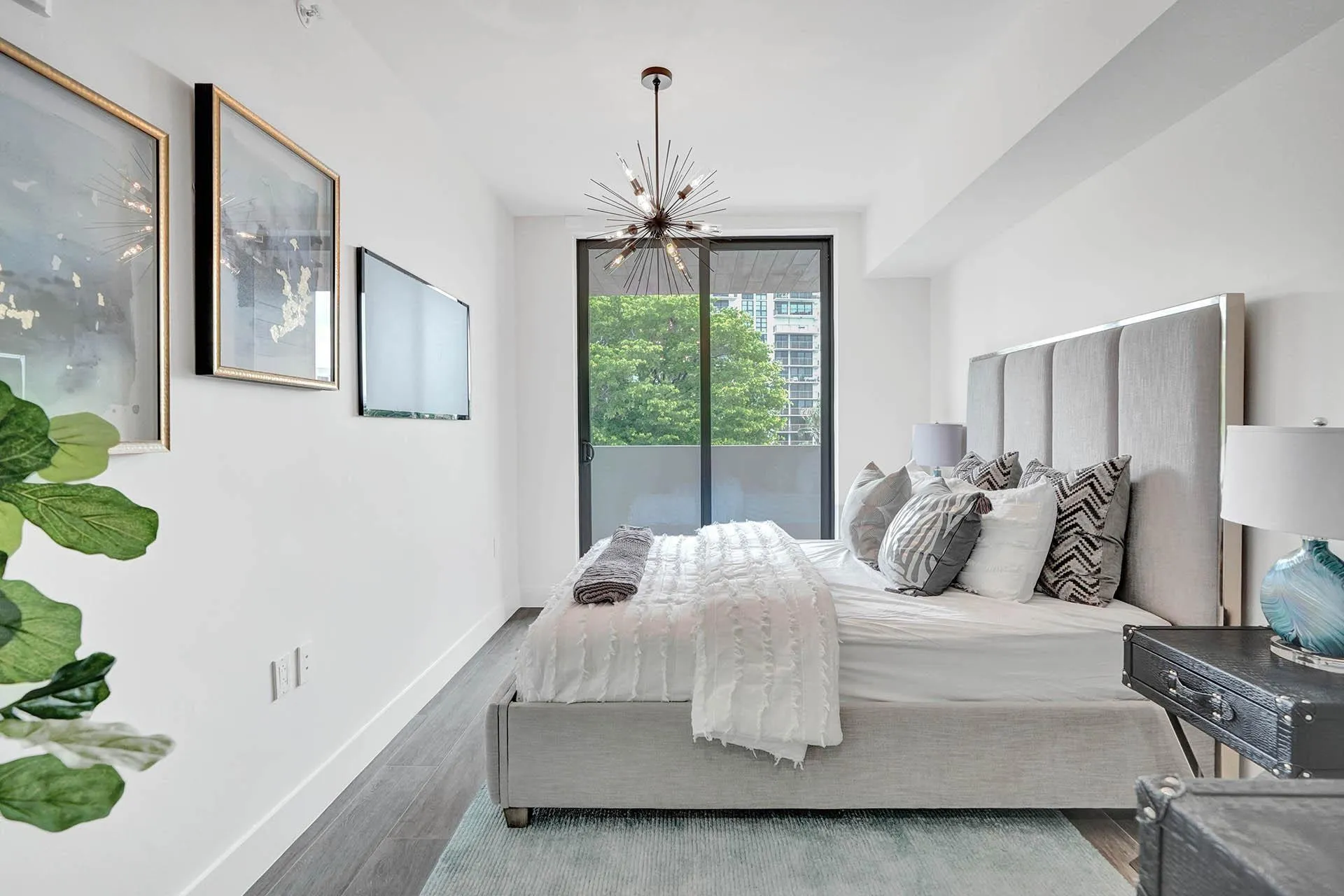 Spacious room featuring wood-finish flooring, a contemporary sputnik chandelier, and a large sliding glass door opening to a private balcony