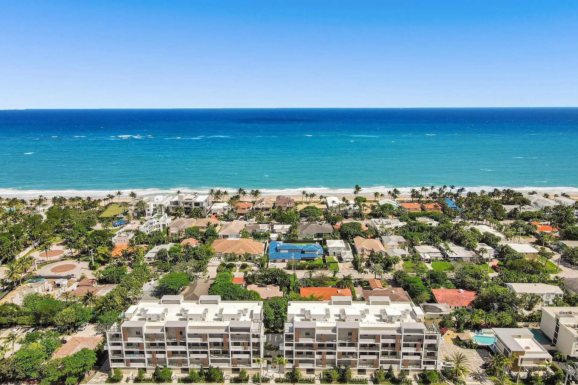 Modern multi-story buildings featuring multiple balconies, set within a coastal community