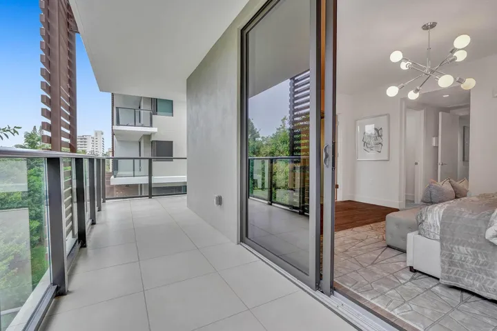 Spacious balcony featuring light-toned tile flooring, clear glass railings, and slatted architectural details