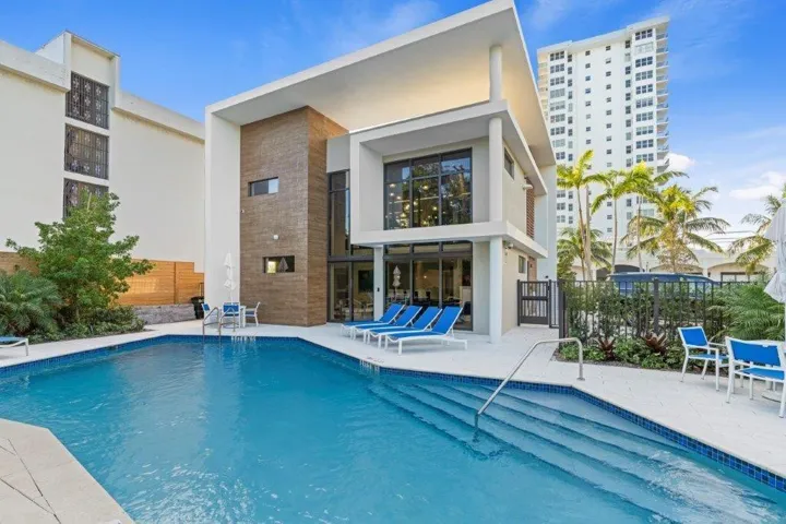 Contemporary home with resort-style outdoor living featuring a sparkling saltwater pool with integrated spa steps, expansive sun deck with lounge seating areas, and professional-grade hardscaping