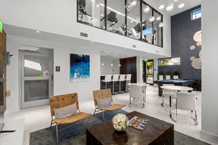 Modern open-concept living space featuring soaring ceilings with skylights, polished concrete flooring, and a dramatic mezzanine level with glass railings