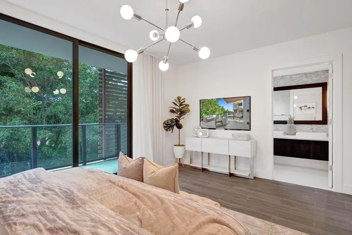 Spacious room featuring floor-to-ceiling sliding glass doors opening to a balcony with a glass railing