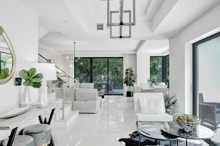 Open-concept living area featuring high-gloss flooring, recessed lighting, and a contemporary stairwell with glass and metal railing