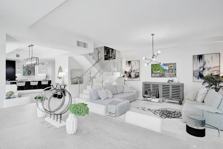 Open-concept living space featuring wood-finish flooring, a contemporary staircase with glass railing, recessed lighting, and a modern kitchen with a large island and pendant lighting