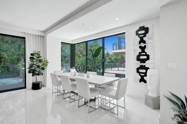 Spacious interior featuring pristine white flooring, an expansive window wall, and a large sliding glass door opening to an outdoor patio