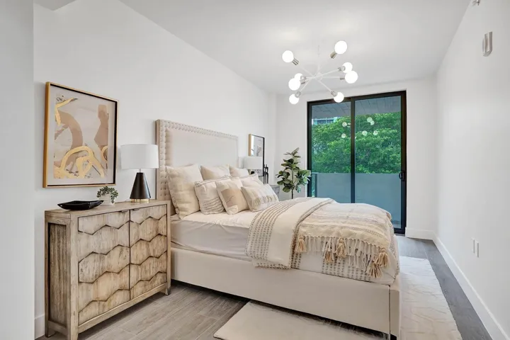 Bedroom featuring a contemporary sputnik chandelier, full-height sliding glass doors, white walls, and wood-finish flooring