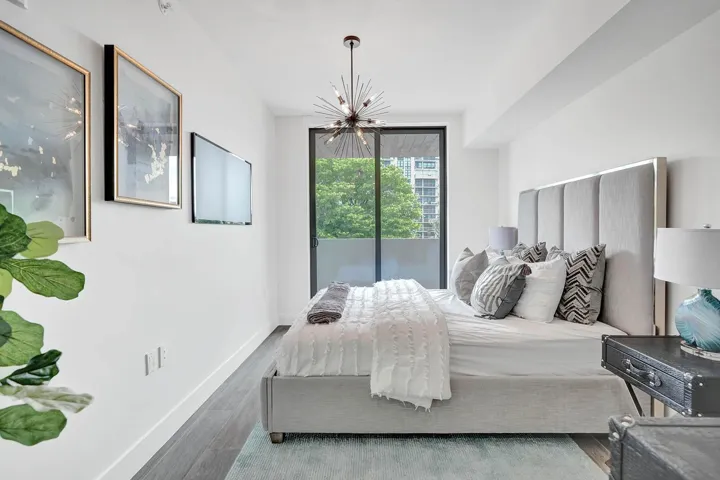 Spacious room featuring wood-finish flooring, a contemporary sputnik chandelier, and a large sliding glass door opening to a private balcony