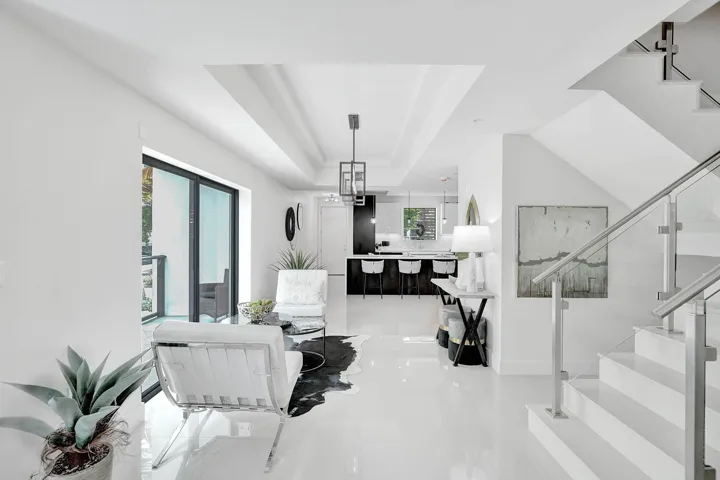 Open-concept interior featuring high ceilings, white tile flooring, and a modern glass and metal staircase