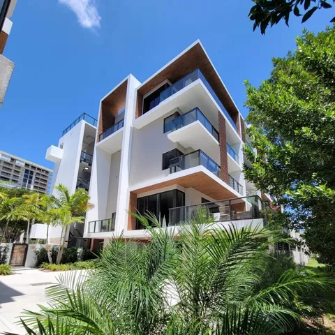 Modern multi-story building featuring white stucco finishes and wood-finish accents