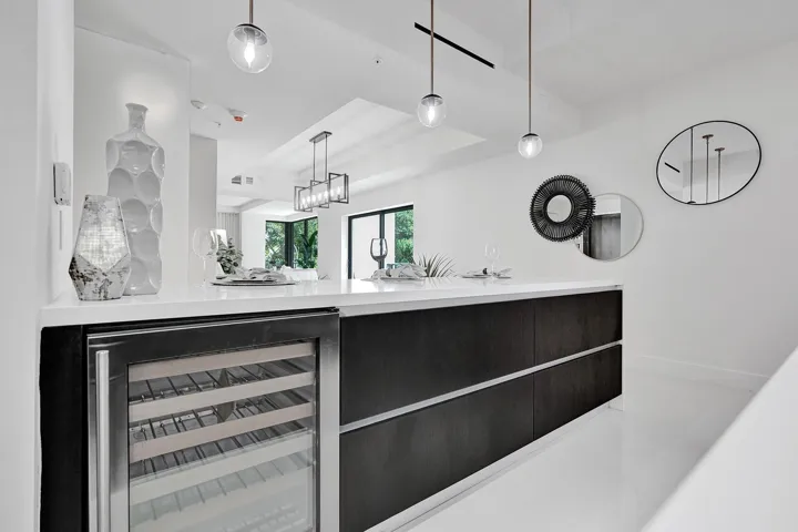 Contemporary kitchen featuring a sleek black cabinetry base with integrated wine cooler, white quartz countertop, and stainless steel hardware