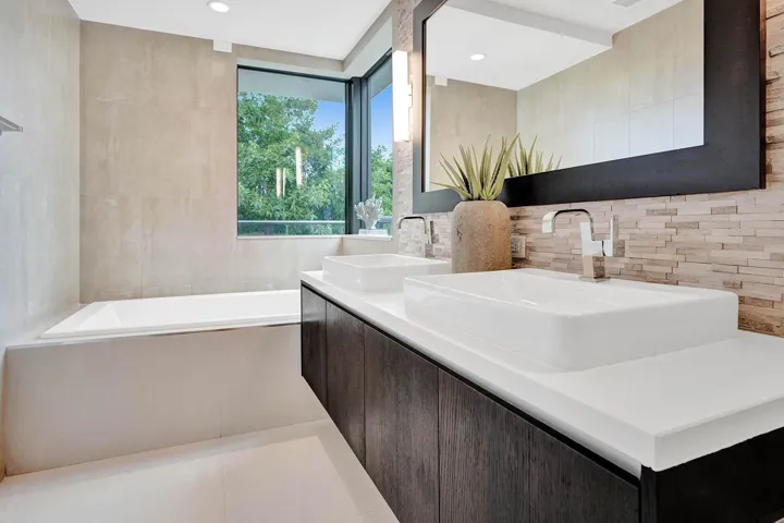 Dual vessel sinks with chrome fixtures set into a dark wood-finish vanity