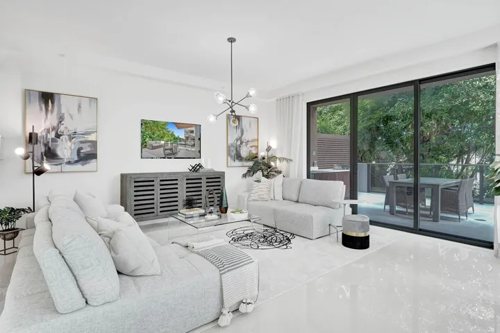 Bright, light-filled living room showcasing floor-to-ceiling glass doors and windows framing lush outdoor greenery