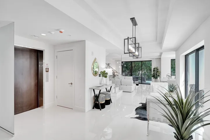 Bright, open-concept interior showcasing polished white flooring, soaring ceilings with geometric pendant lighting, and abundant natural light from multiple windows