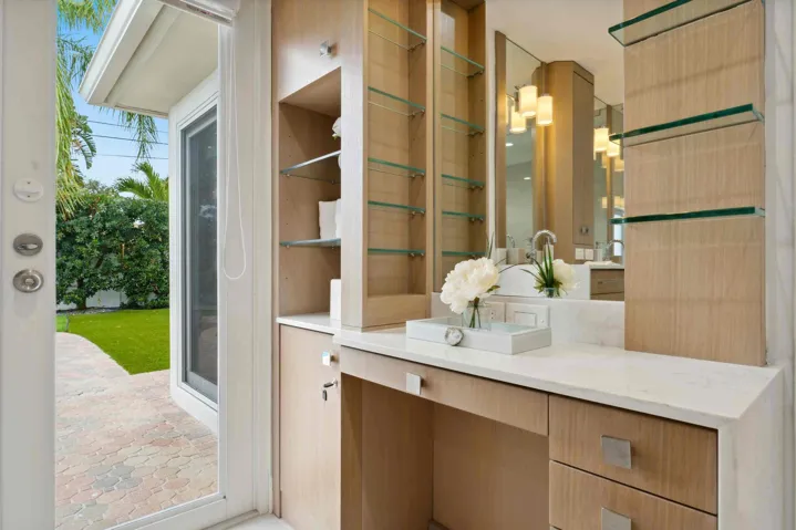 Built-in vanity with wood-finish cabinetry, a light-toned countertop, and integrated sink
