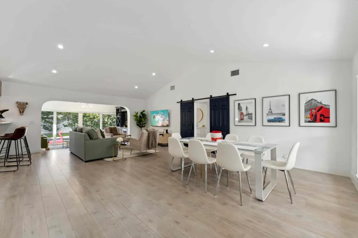 Open-concept living space showcasing wood-finish flooring, recessed ceiling lighting, and abundant natural light from large windows
