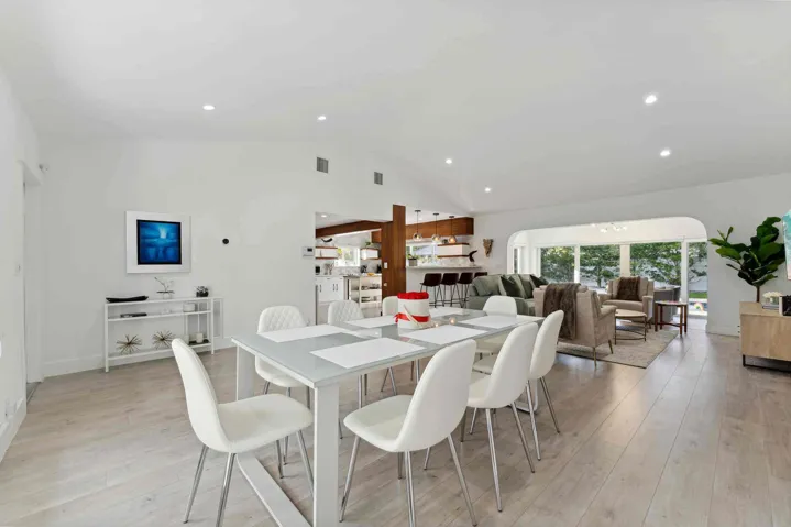 Open-concept living space featuring a wood-finish plank floor throughout, recessed ceiling lighting, and seamless integration of dining and kitchen areas