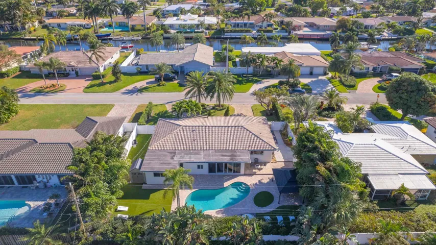 Residential property featuring a swimming pool, mature landscaping, and a tile roof