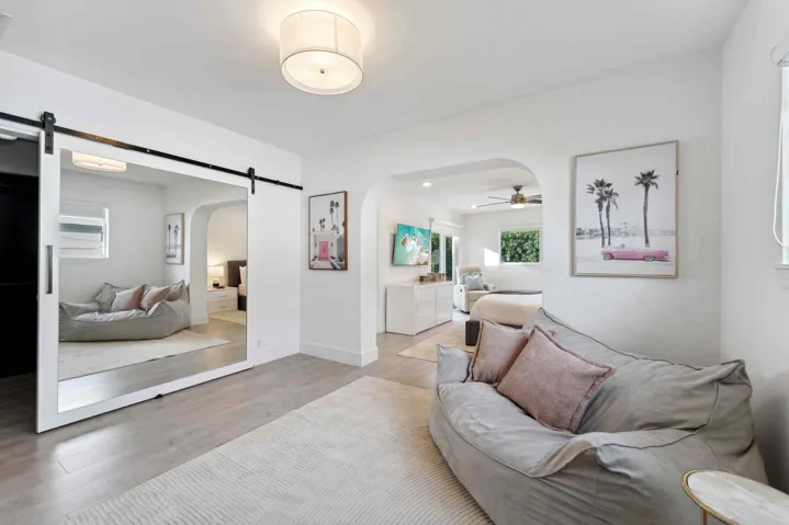 Open-concept interior featuring light wood-finish flooring, a contemporary ceiling light fixture, and an arched entryway