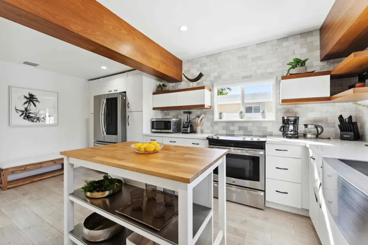Contemporary kitchen featuring white cabinetry, stainless steel appliances, a butcher block island, light wood-finish flooring, and a subway tile backsplash