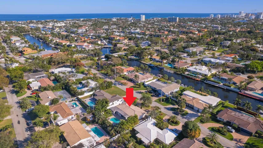 Aerial perspective of a neighborhood featuring residential properties, waterways, and distant coastal waters