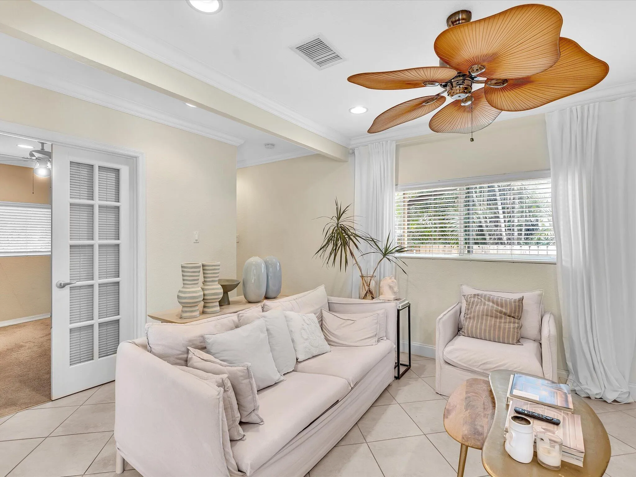 Neutral wall paint, recessed lighting, tile flooring, crown molding, and a ceiling fan with palm leaf-style blades