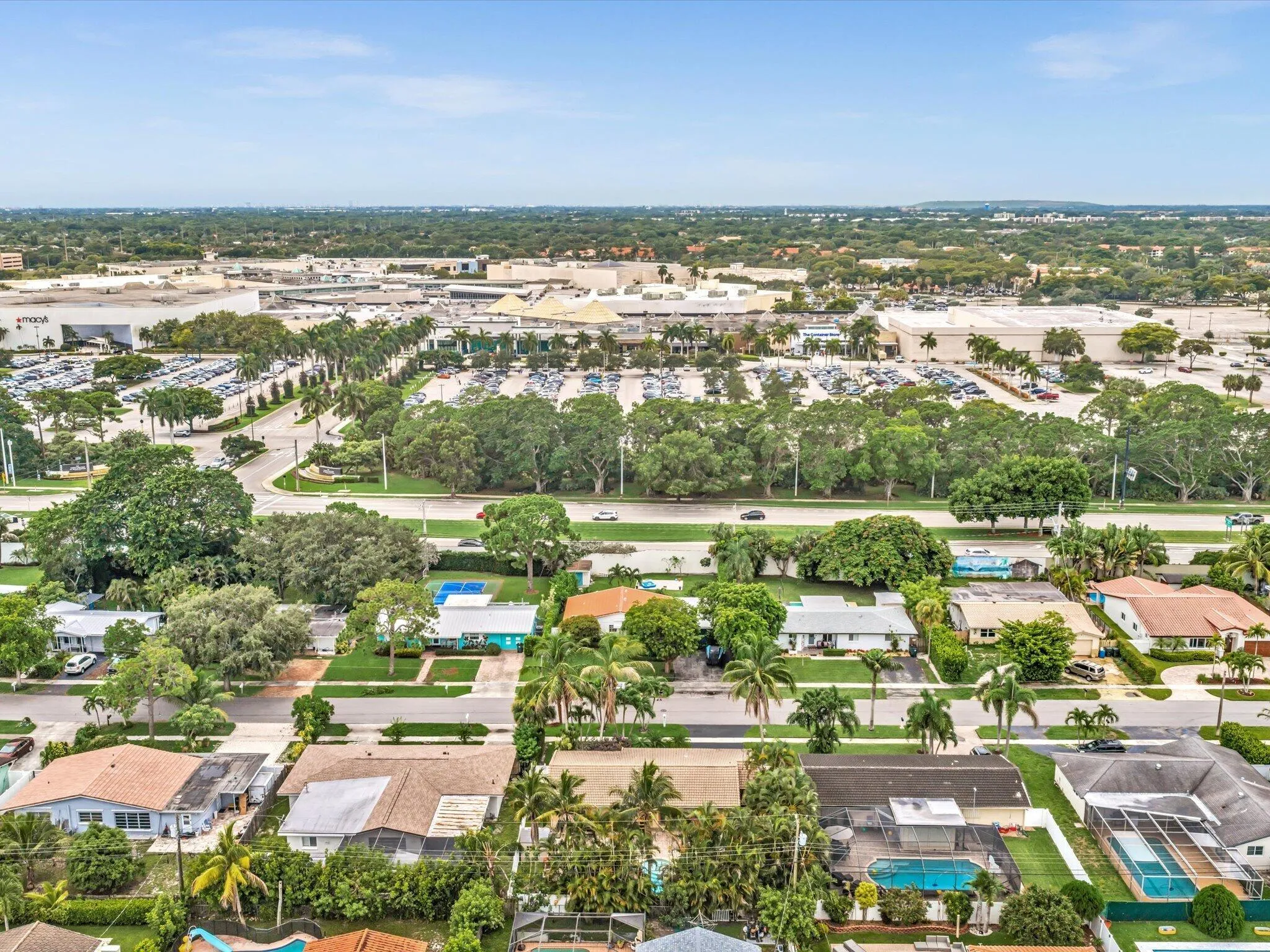 Aerial perspective showcasing a residential neighborhood with mature trees, established landscaping, and multiple properties featuring private swimming pools