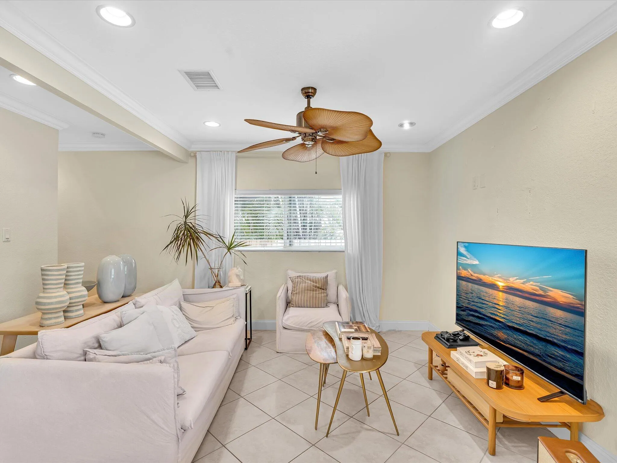 Bright, light-filled bedroom featuring recessed ceiling lighting, a ceiling fan with wood-finish blades, tile flooring, and large windows with sheer drapery