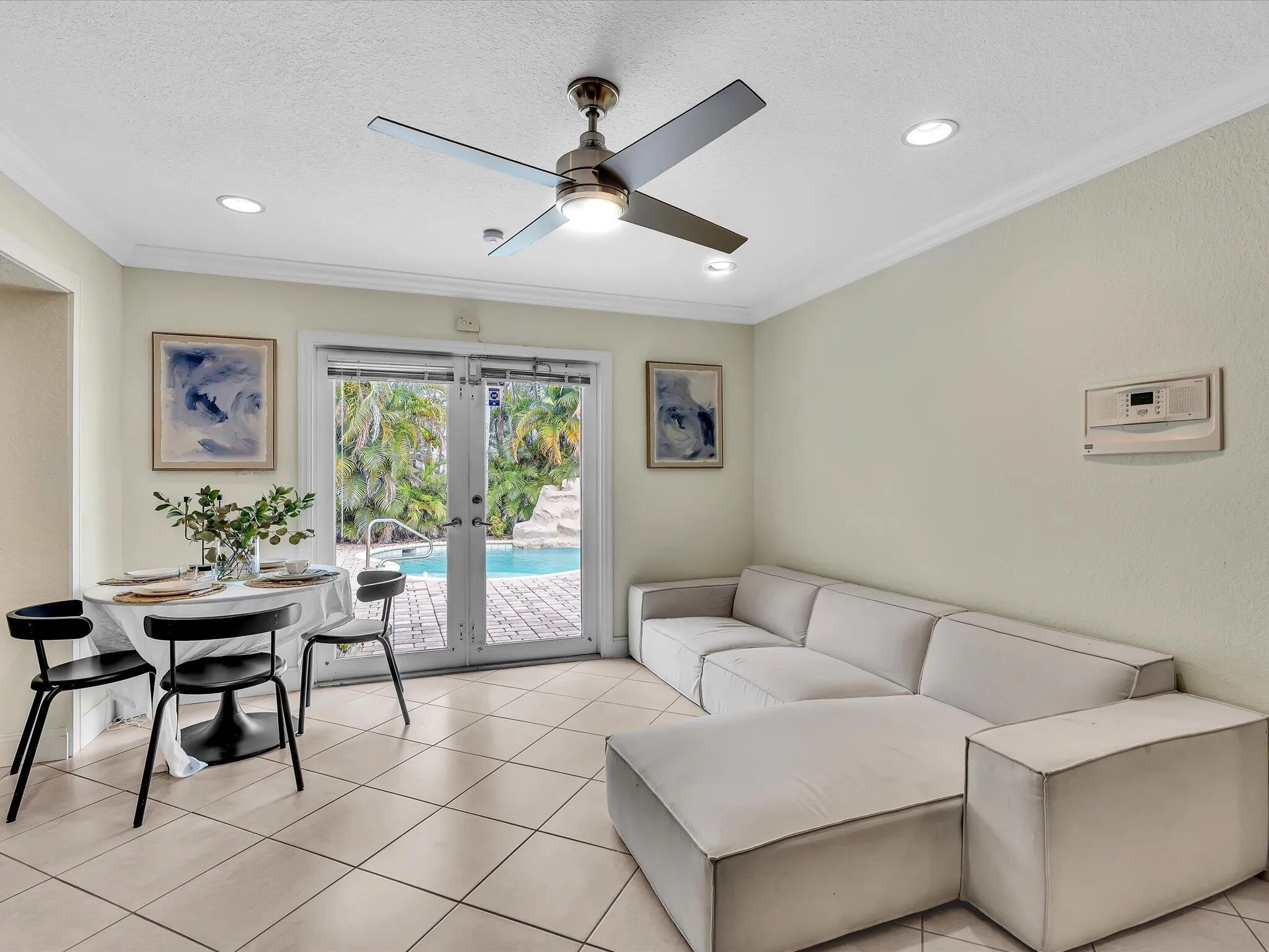 Tiled flooring, crown molding, ceiling fan, recessed lighting, and patio doors leading to a pool area