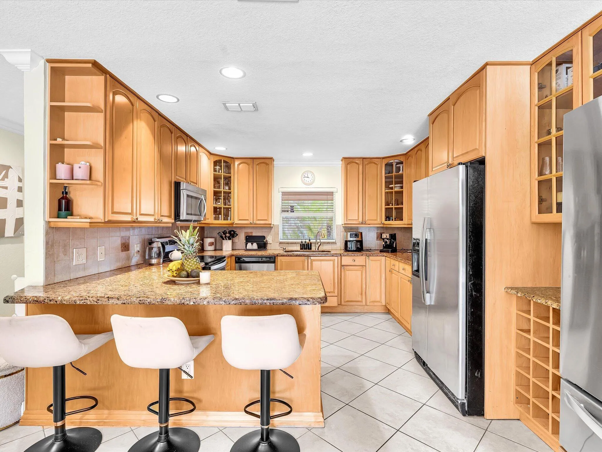 Kitchen featuring light wood cabinetry, granite-style countertops, stainless steel appliances, and tiled flooring