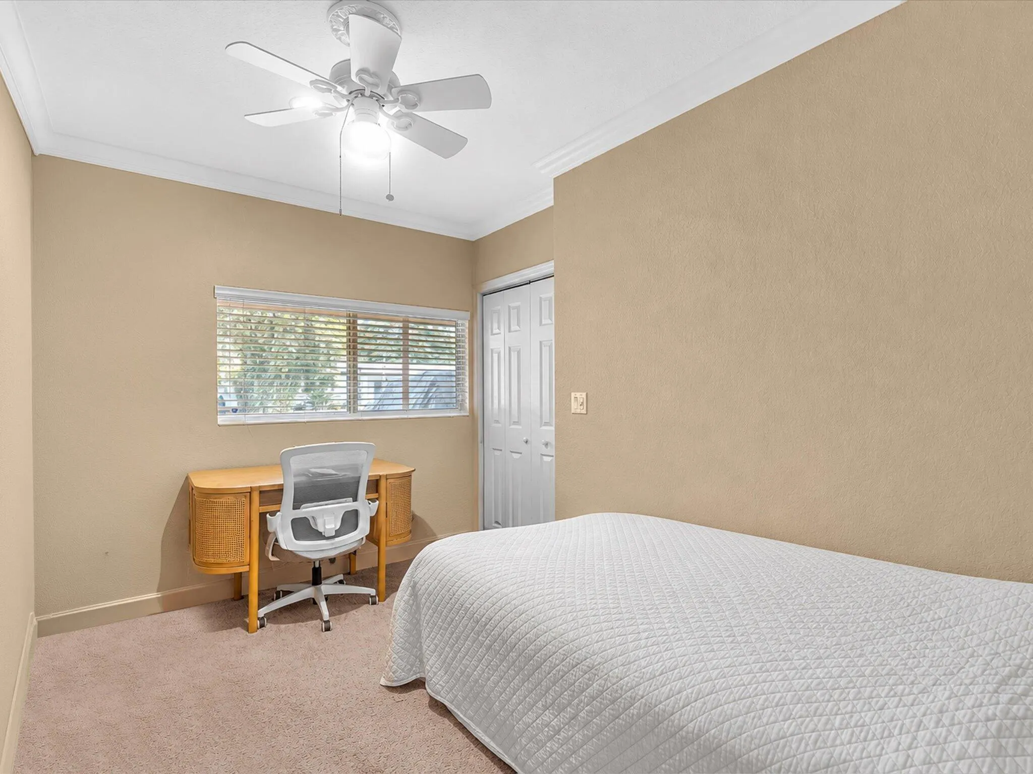 Recessed window with blinds, ceiling fan with integrated lighting, textured wall finish, crown molding, and neutral carpet flooring
