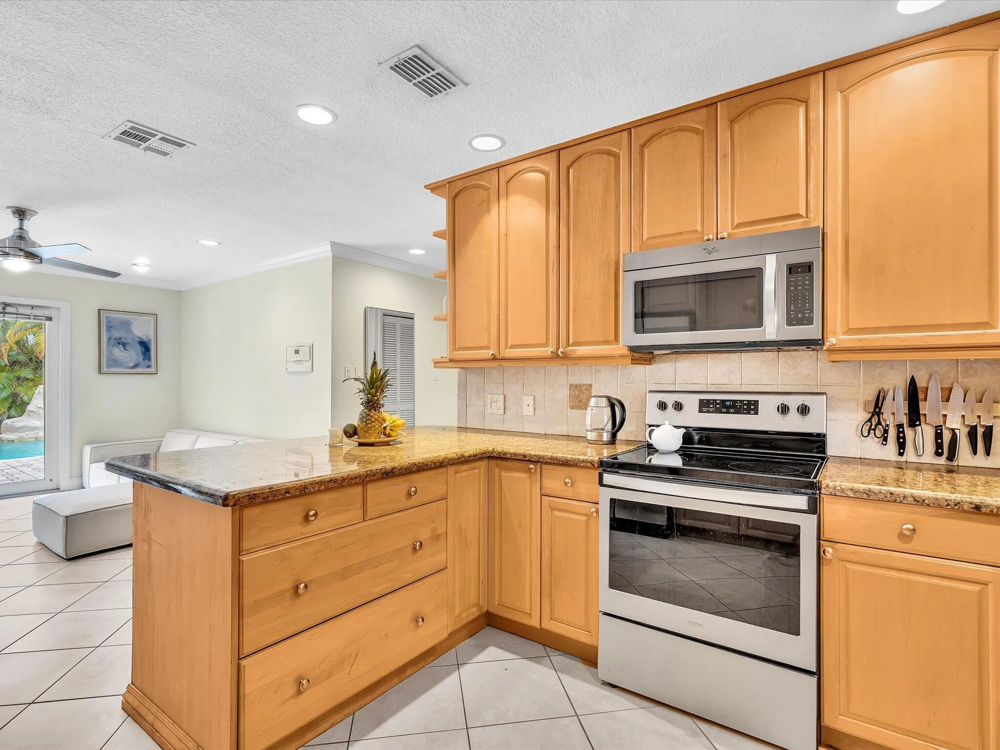 Kitchen featuring wood cabinetry, stainless steel appliances, granite countertops, and tiled flooring