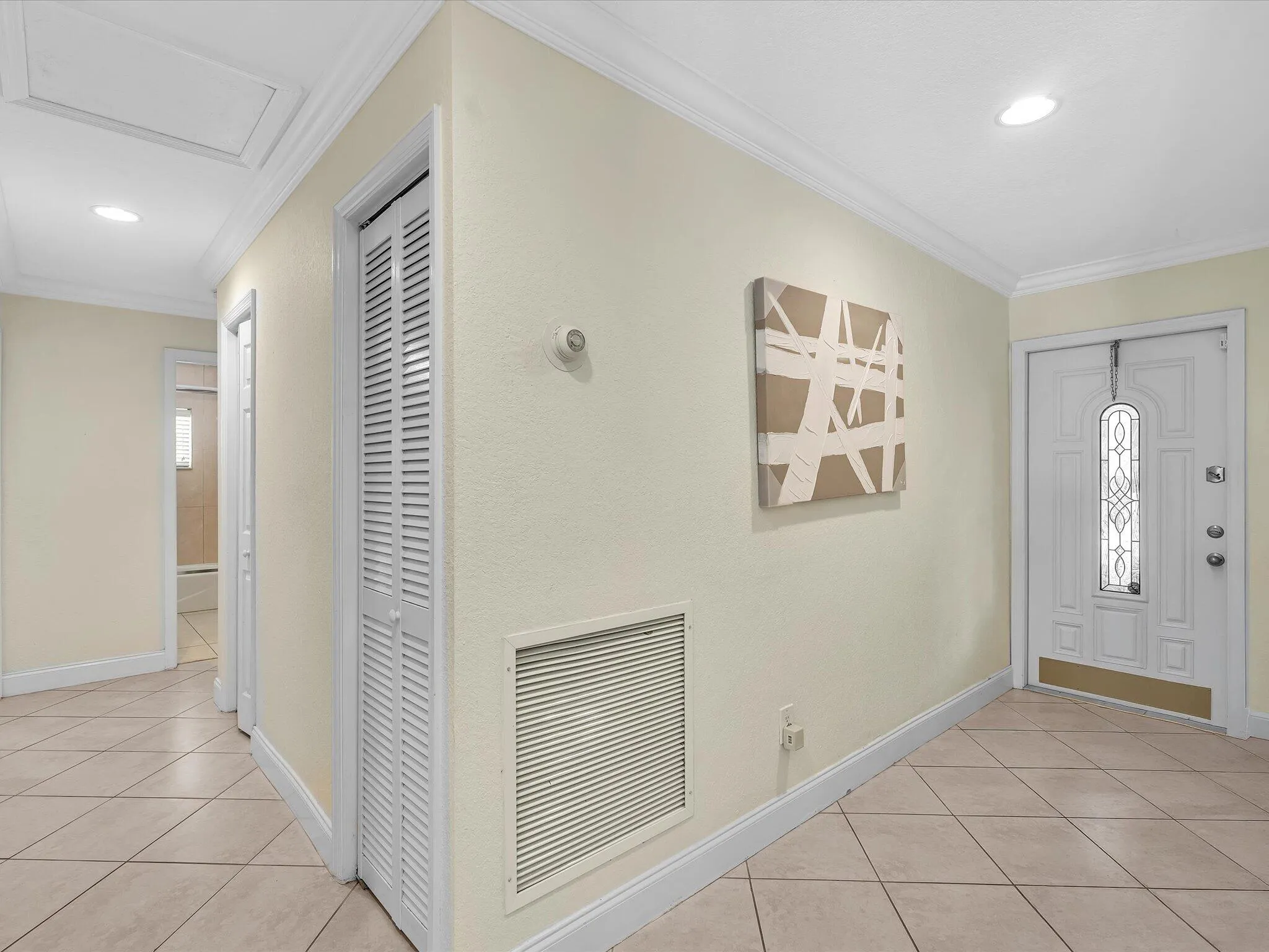 Tiled flooring, white trim, recessed lighting, louvered bi-fold door, and front entry door with decorative glass inserts