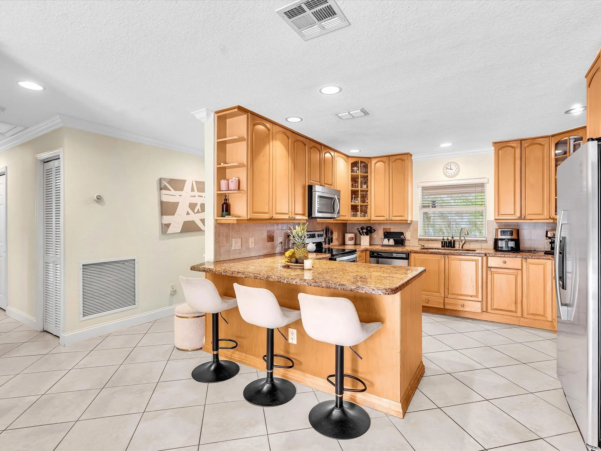 Kitchen featuring an integrated breakfast bar, wood-finish cabinetry, recessed lighting, and diagonal tile flooring