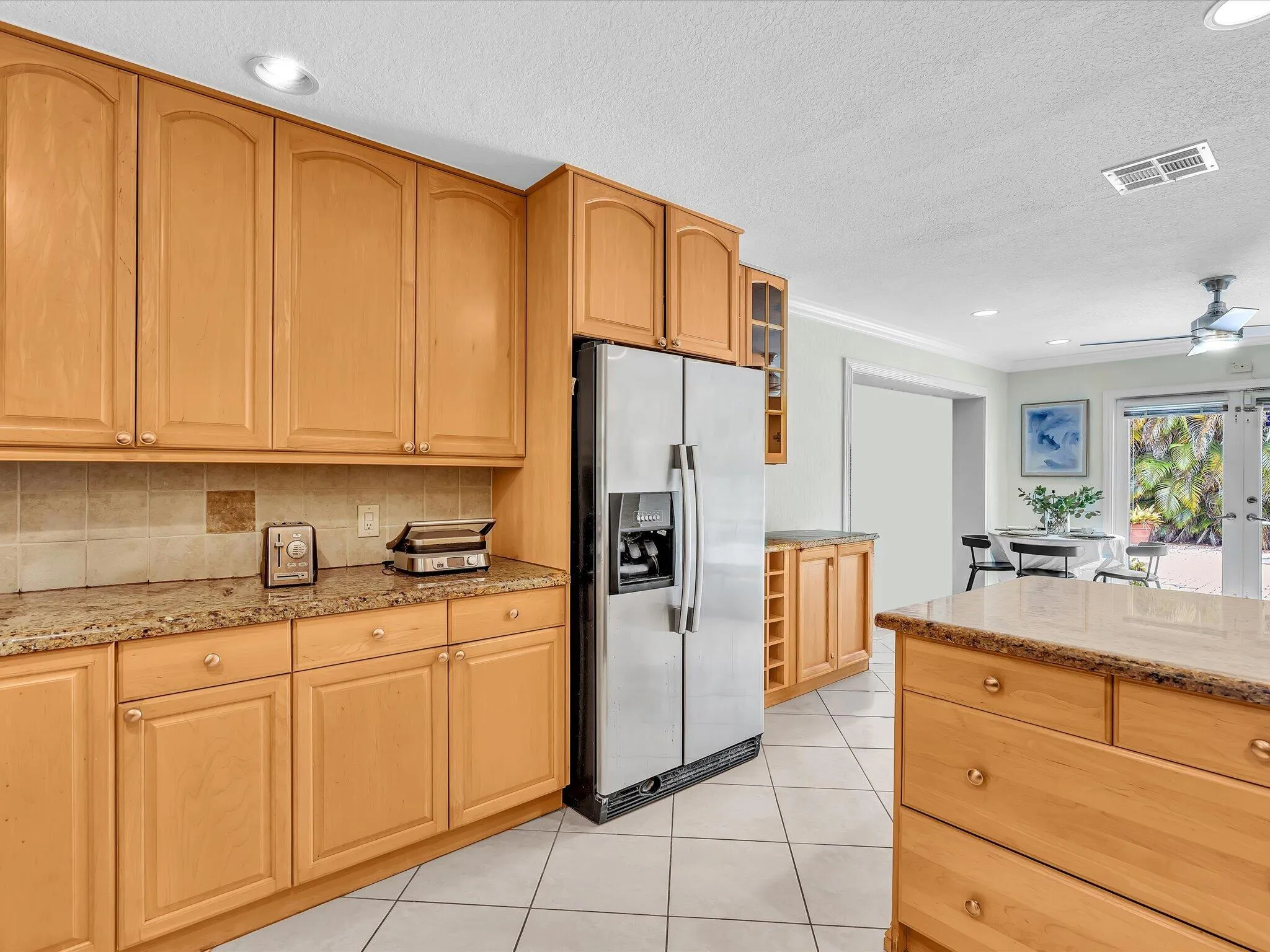 Wood-finish cabinetry, tile flooring, stainless steel appliances, recessed lighting, and a kitchen island with storage