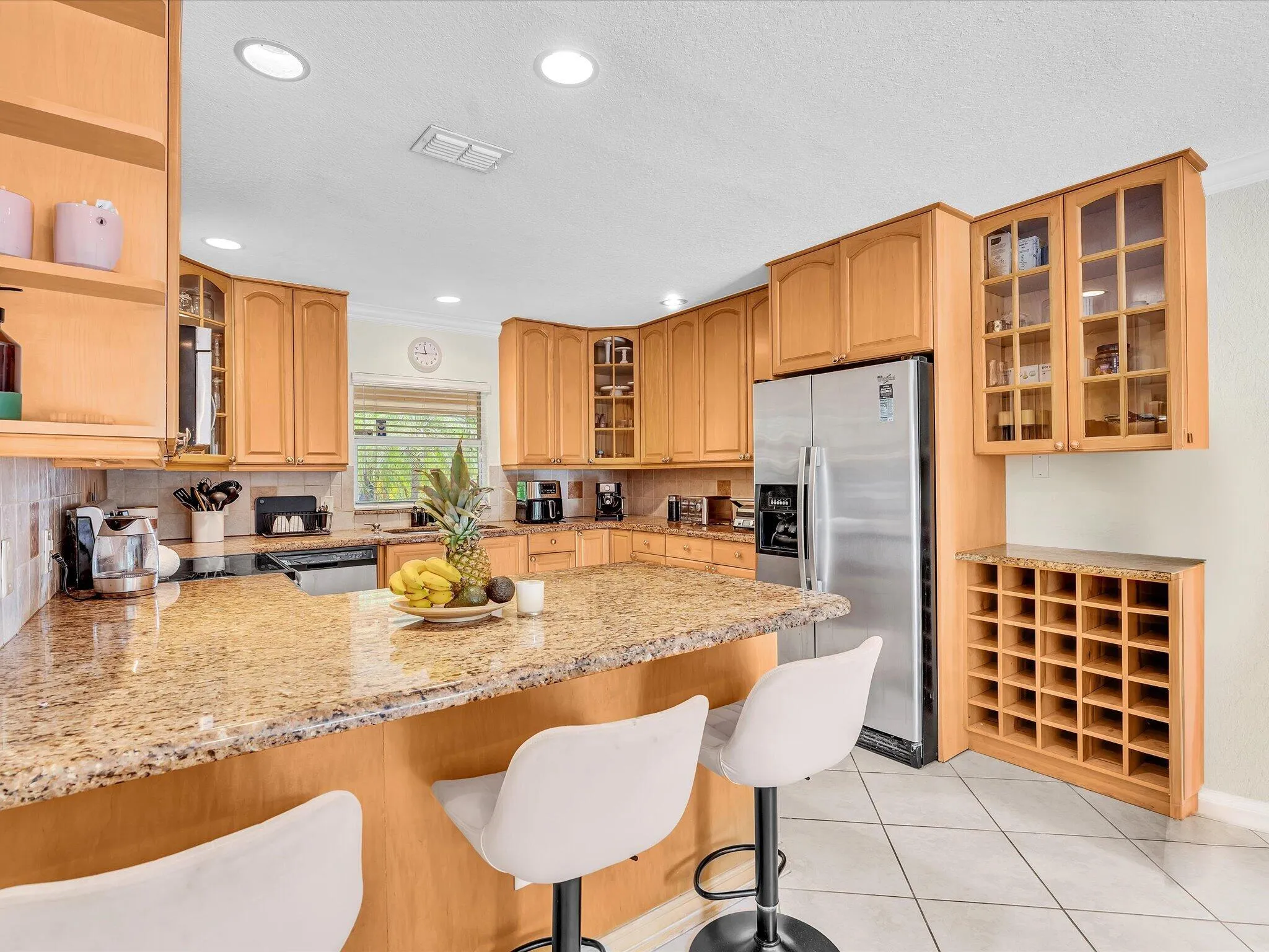 Kitchen featuring wood-finish cabinetry, granite countertops, tile flooring, stainless steel appliances, and recessed lighting