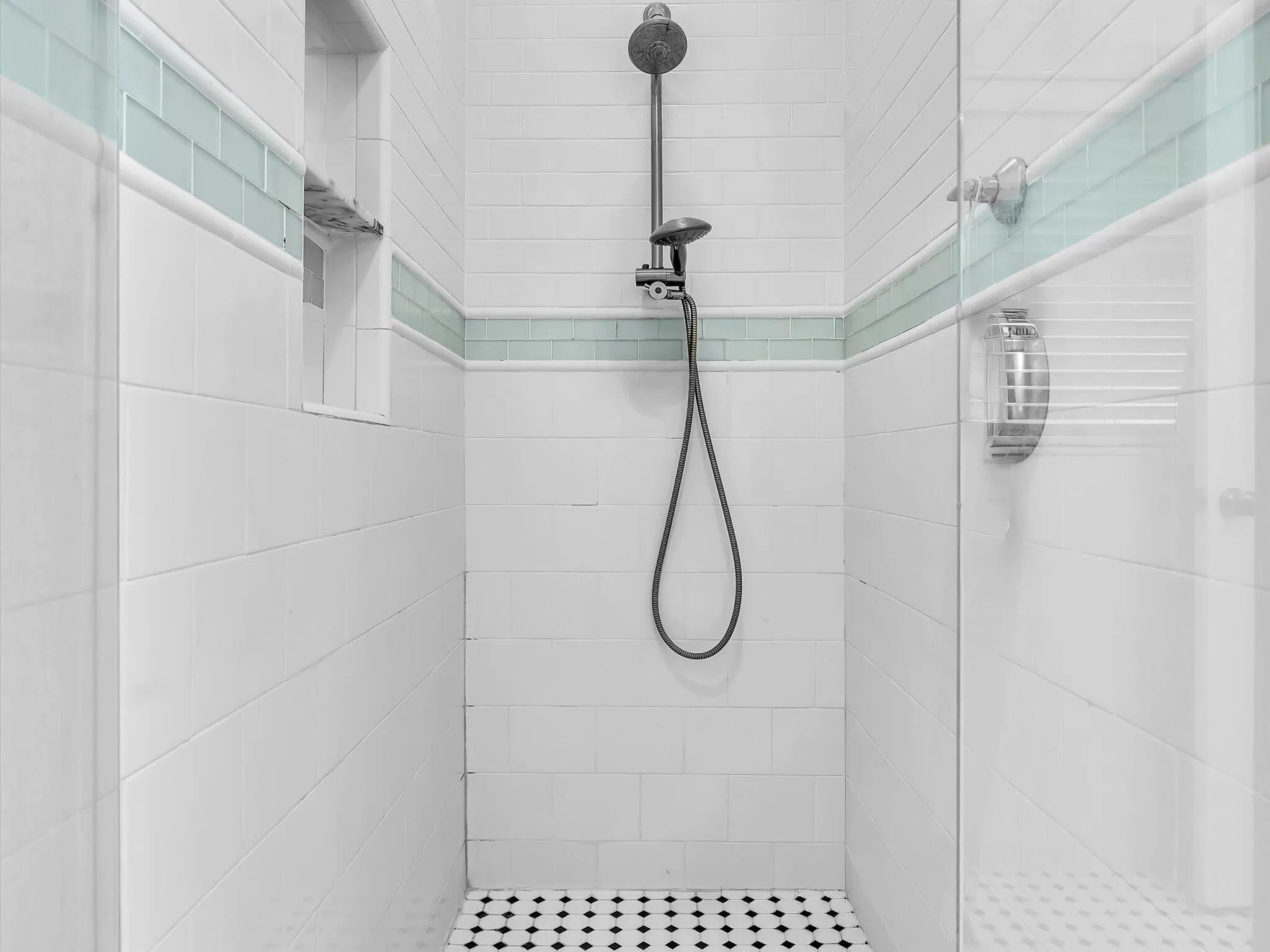 Tiled shower enclosure featuring a fixed rainfall shower head, handheld shower, and a built-in shelf