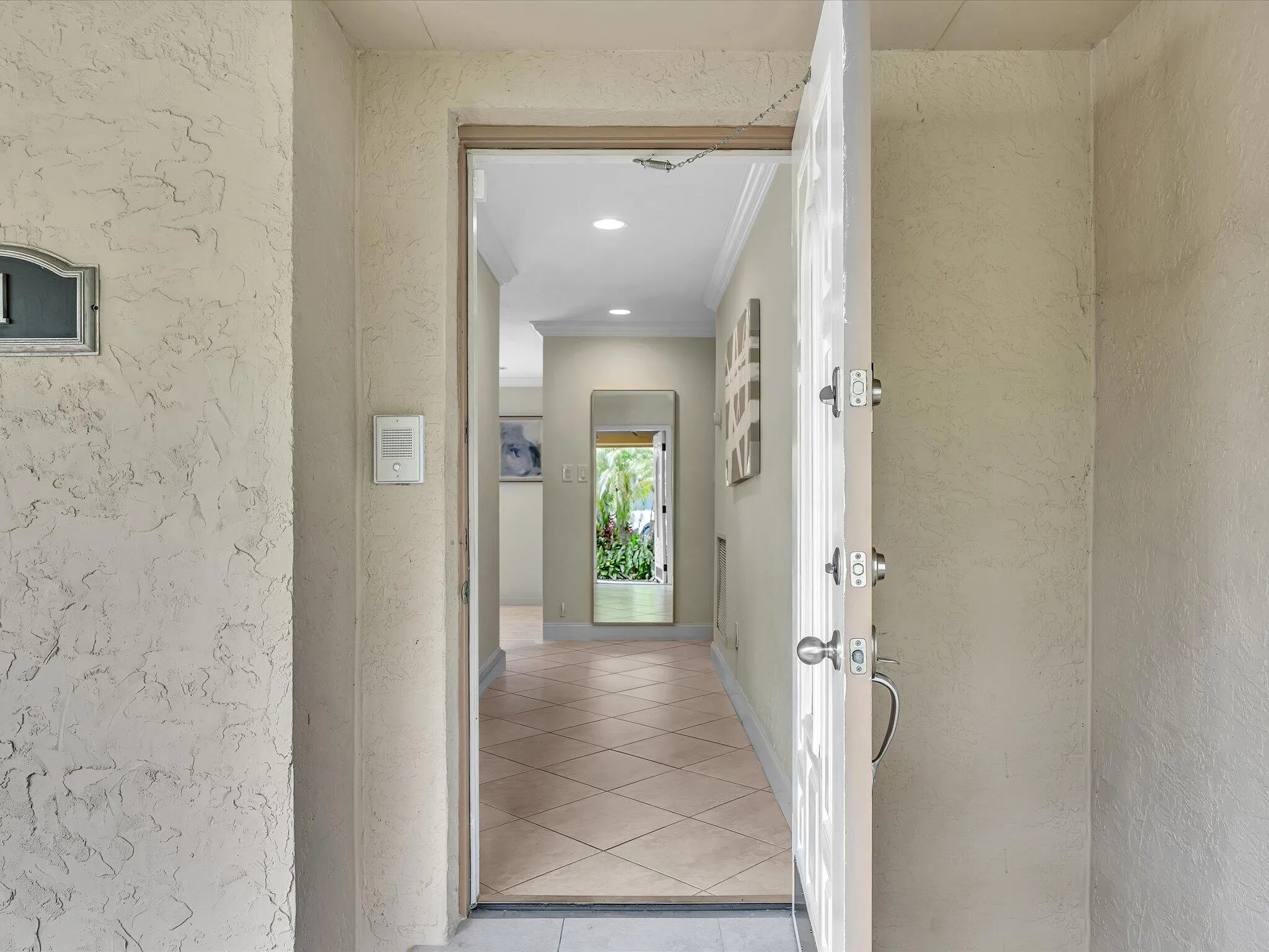Textured exterior wall finish, solid entry door with multiple locks, tiled flooring, recessed lighting, and crown molding
