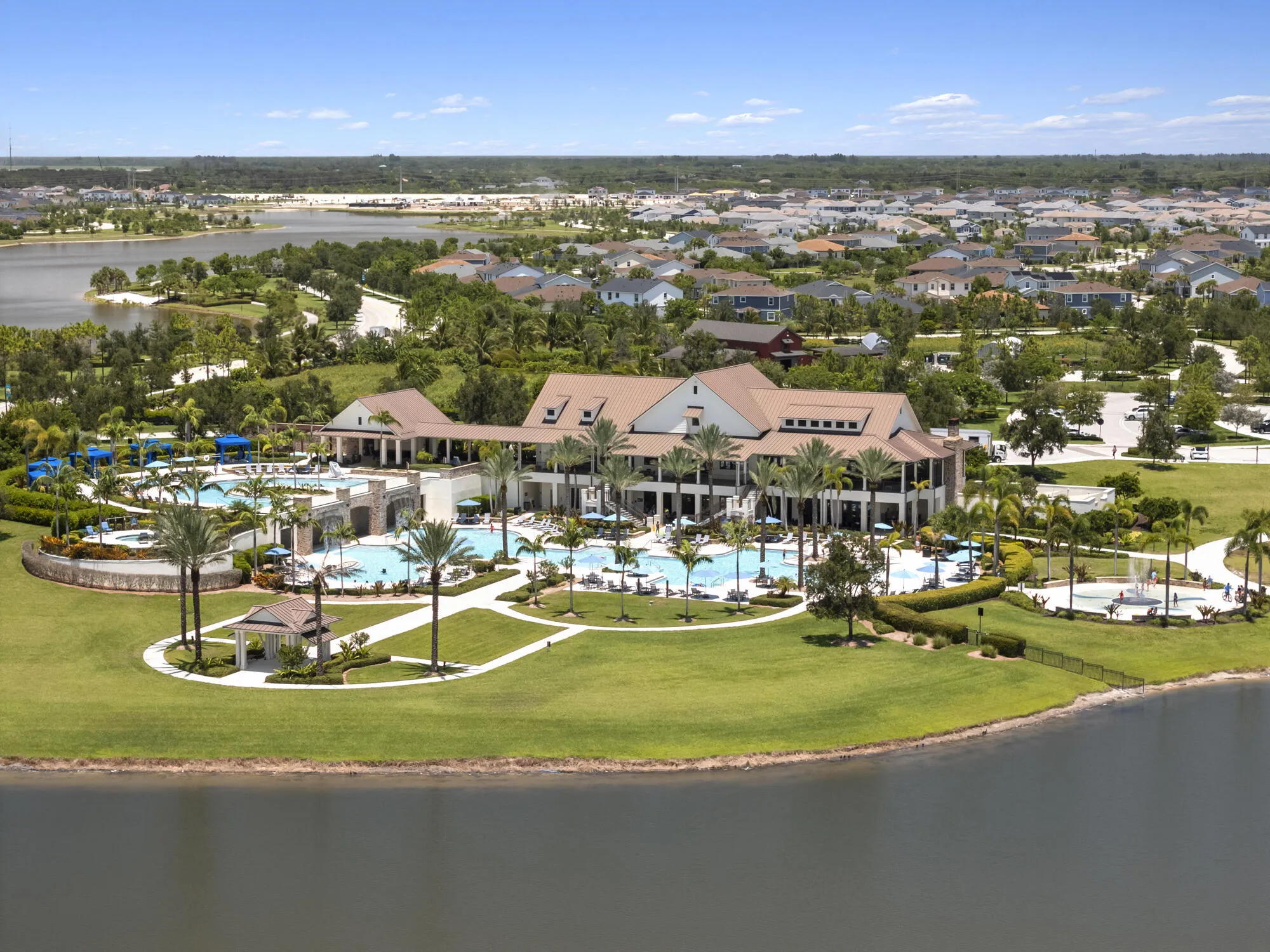 Expansive recreational amenity center featuring multiple swimming pools, a central clubhouse, and extensive manicured landscaping