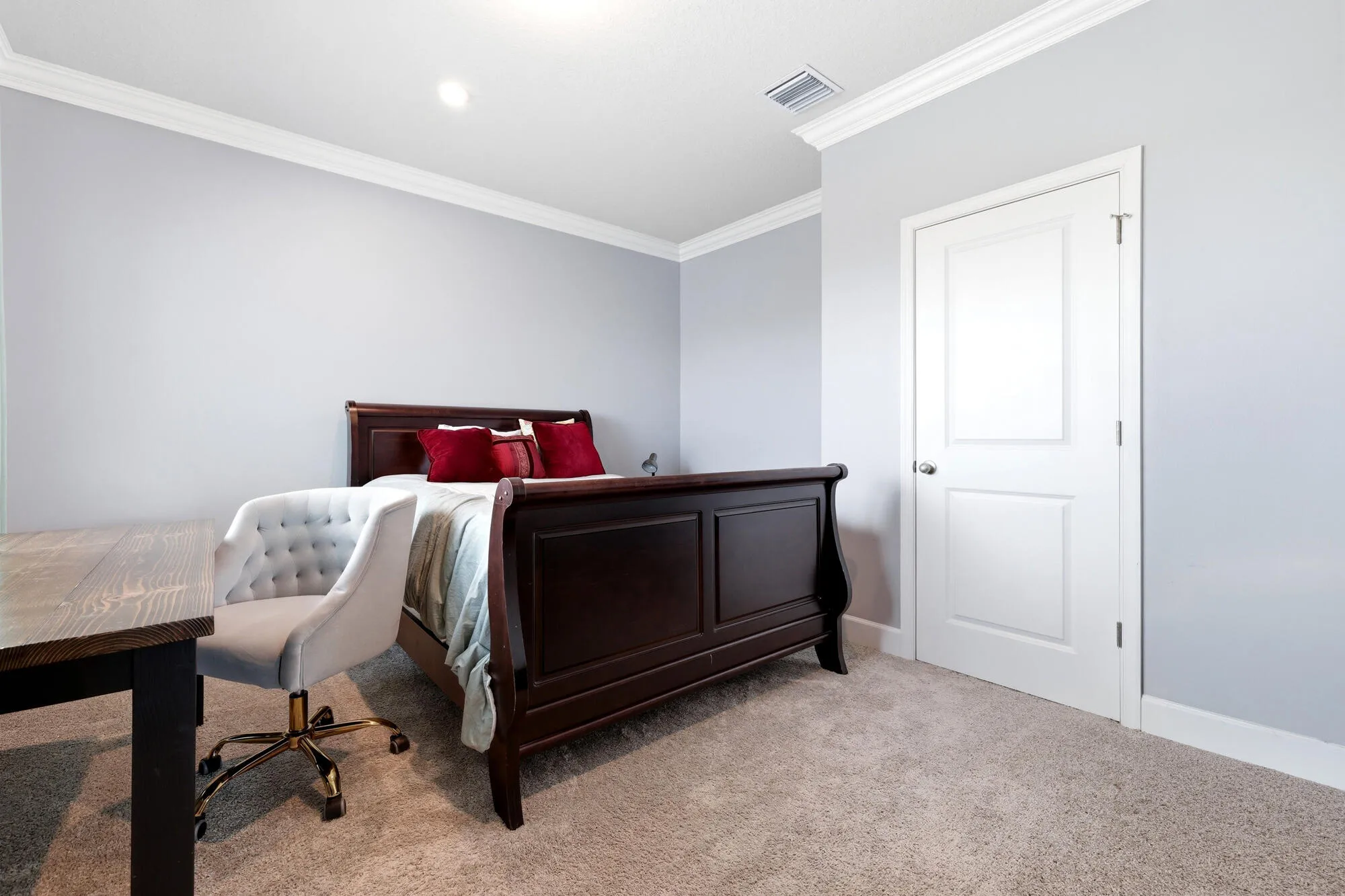 Bedroom featuring light gray walls, white crown molding, white baseboards, and neutral-toned carpeting