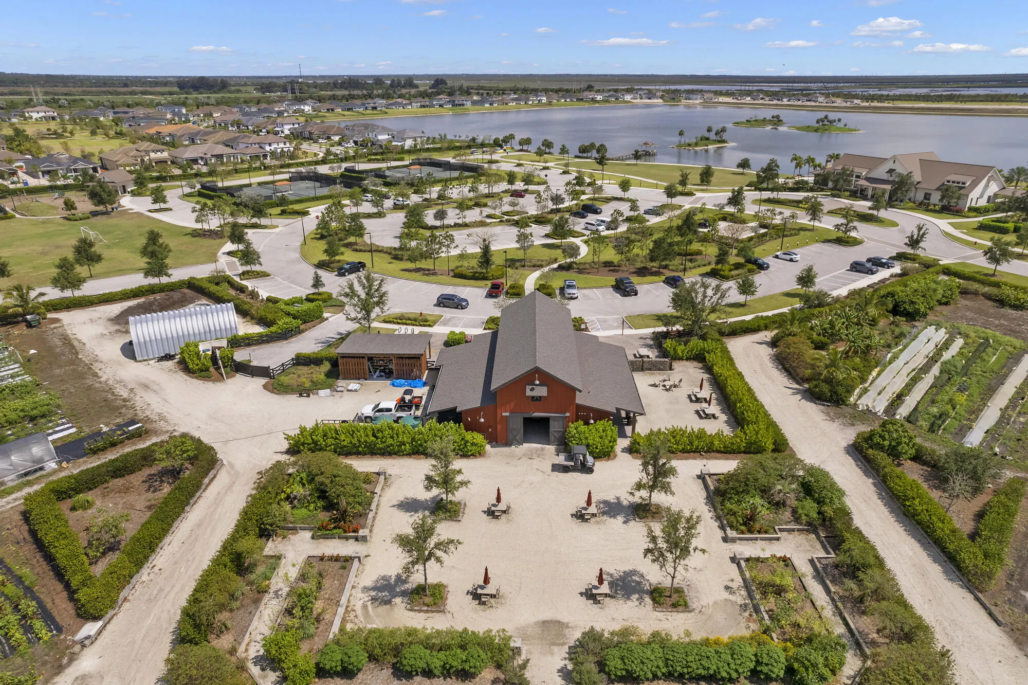 Arden's community farm and working garden, featuring raised planting beds, fresh produce rows, shaded seating areas, and the farm barn — a beloved gathering spot for residents who enjoy farm-to-table living, gardening, and outdoor community events.