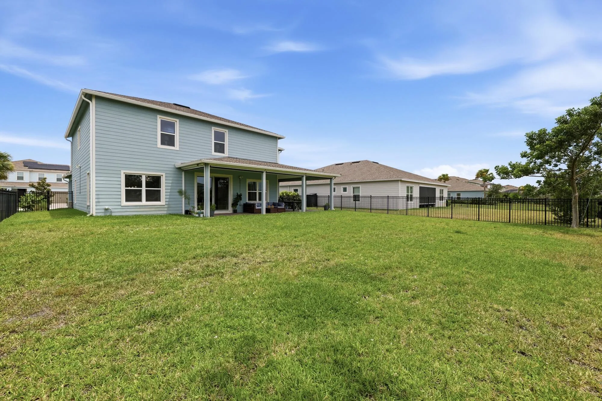 Expansive green lawn surrounds a two-story home with light blue siding