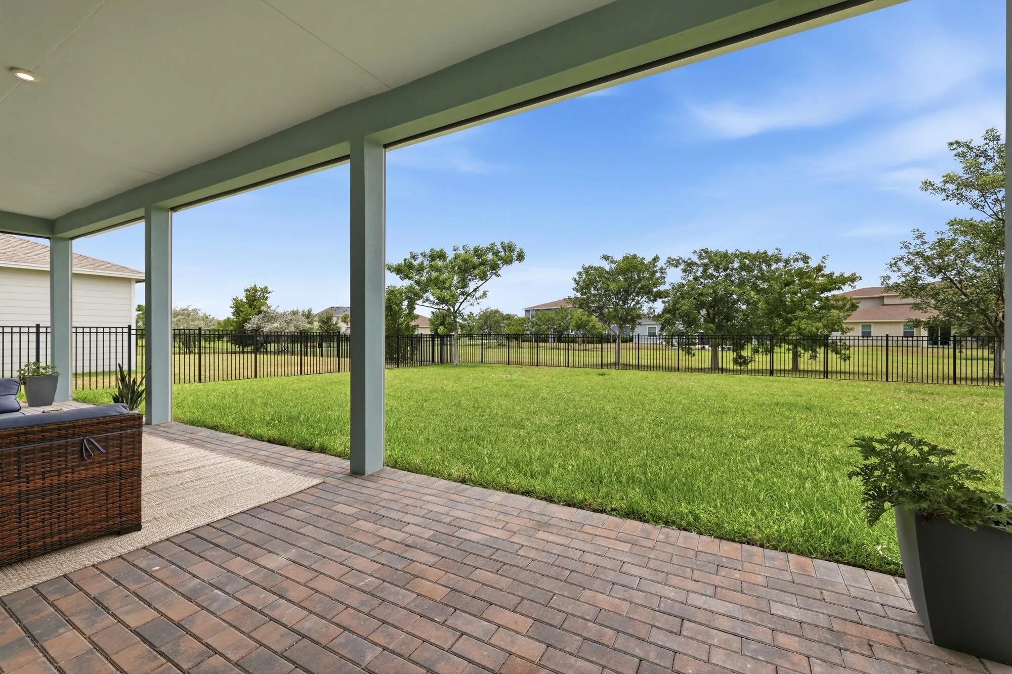 Covered patio featuring brick paver flooring, recessed lighting, and a spacious grassy yard