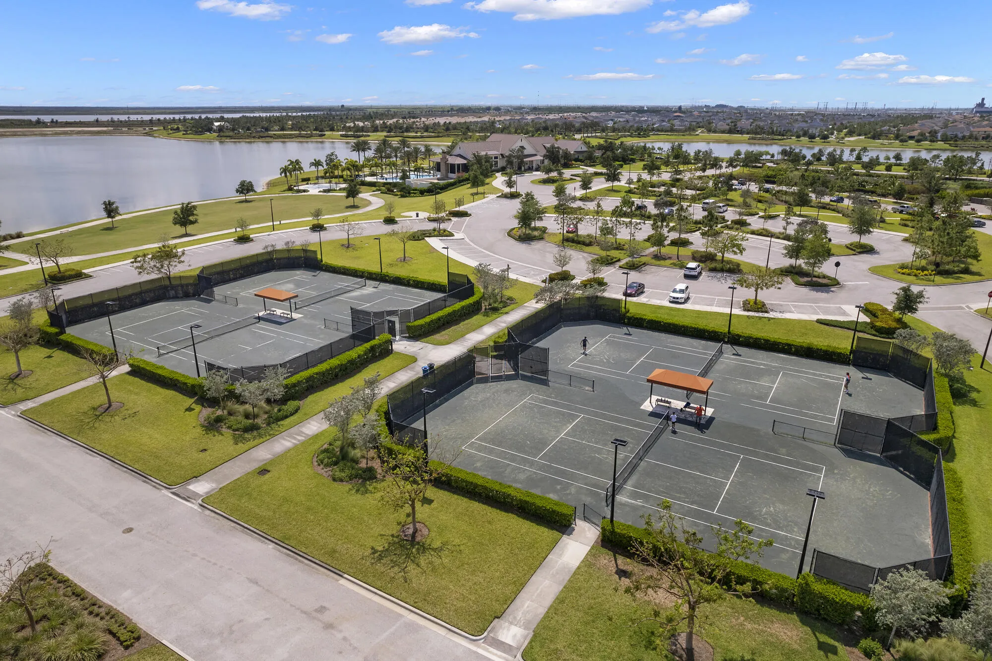 Two hard surface tennis courts with green perimeter fencing and lighting
